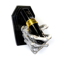 Skeleton hand on a coffin shaped plate to be mounted on a wall to hold a tattoo machine. Currently holding a Fk irons Flux tattoo machine