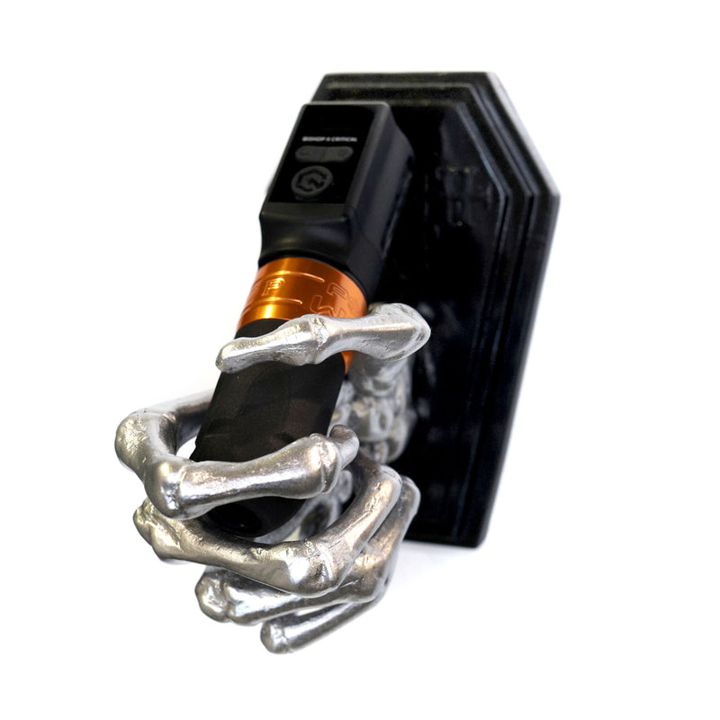 Skeleton hand on a coffin shaped plate to be mounted on a wall to hold a tattoo machine. Currently holding a Fk irons Flux tattoo machine